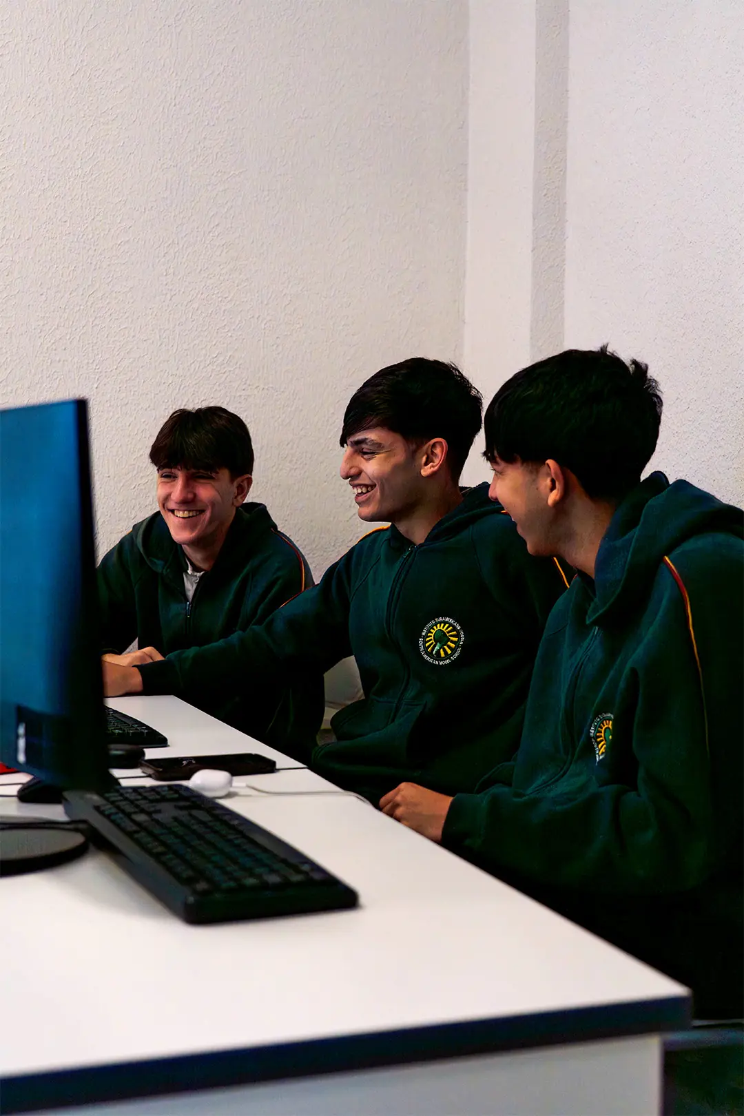 Tres estudiantes del Nivel Secundario del IESM trabajando juntos frente a una computadora